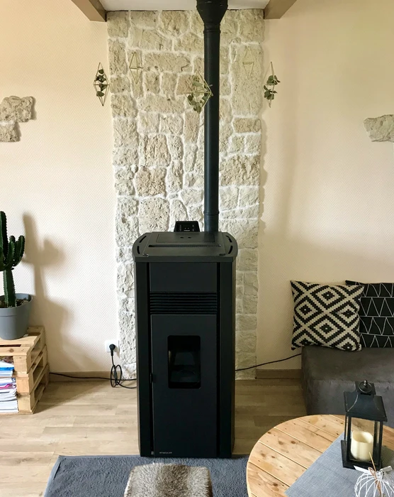 Salon moderne avec poêle à granulés noir, posé sur dallage, raccordé par un conduit de fumée noir vertical