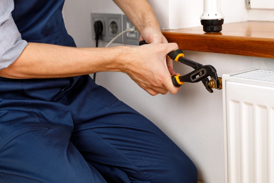 Plombier professionnel travaillant sur installation de chauffage en intérieur